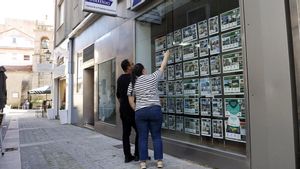 Una pareja observa el escaparate de una inmobiliaria en Sanxenxo.