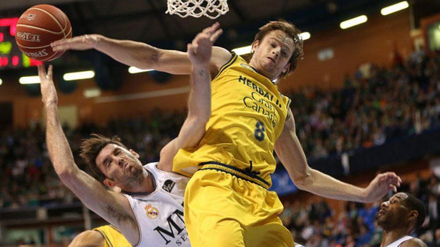 El escolta del Real Madrid Rudy Fernandez (i) recibe un tapón del alero australiano del Herbalife Gran Canaria Brad Newley (d).