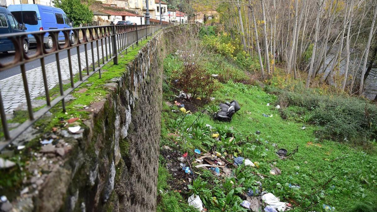 Basuras y enseres junto al río, en el barrio de San Lázaro de Plasencia.