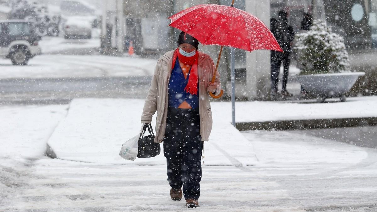 Una mujer camina por la calle durante una nevada en Pedrafita do Cebreiro