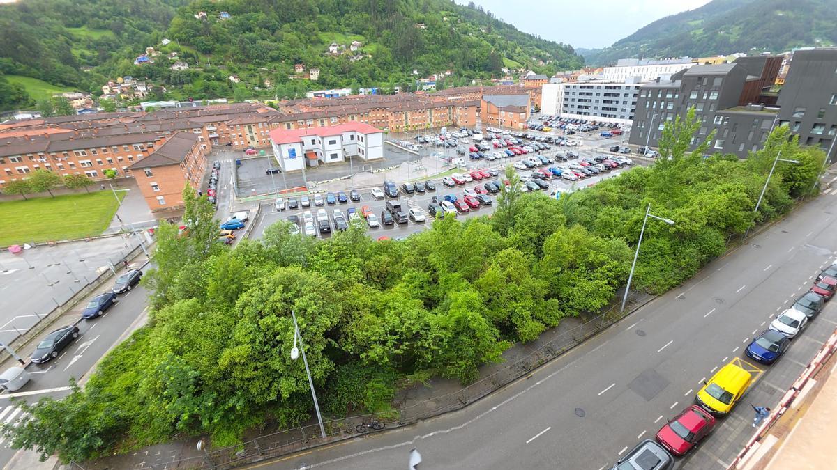 la parcela sin urbanizar de La Mayacina, llena de maleza, vista desde uno de los bloques de viviendas anexos.