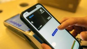 Nuevos sistemas de pago en un comercio de proximidad, un cliente paga con el móvil