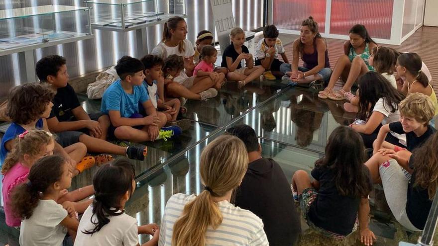 Un grupo de alumnos atiende a la monitora en un taller fuera del aula.