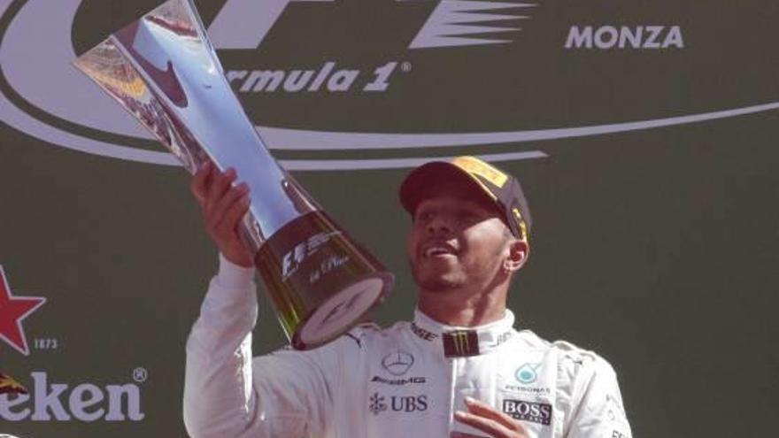 Lewis Hamilton (Mercedes) levanta el trofeo por encima de la marca Ferrari, ayer en Monza.