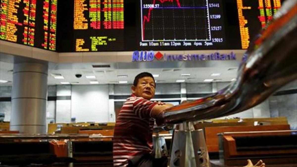 Un inversor sigue los monitores de la bolsa en Kuala Lumpur, Malasia, ayer martes.
