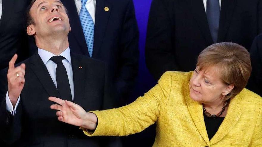 Macron y Merkel reaccionan al sobrevuelo de un dron filmador durante la foto de familia.