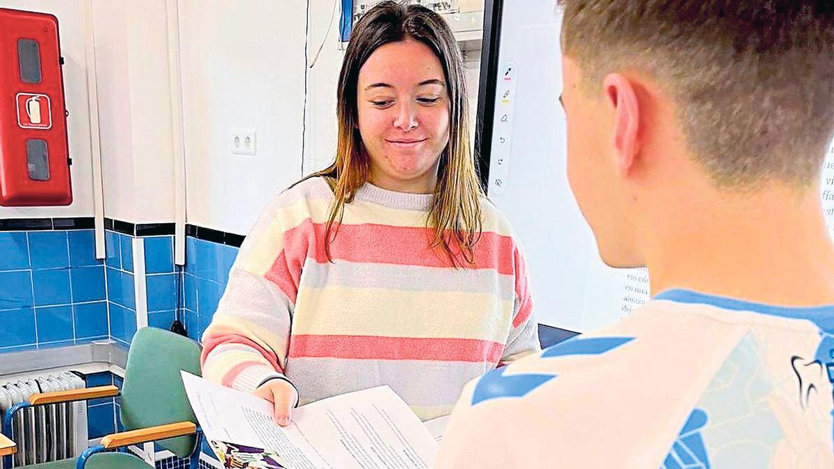 La profesora Lucía Márquez entrega un examen corregido a uno de sus alumnos con un cromo de premio.