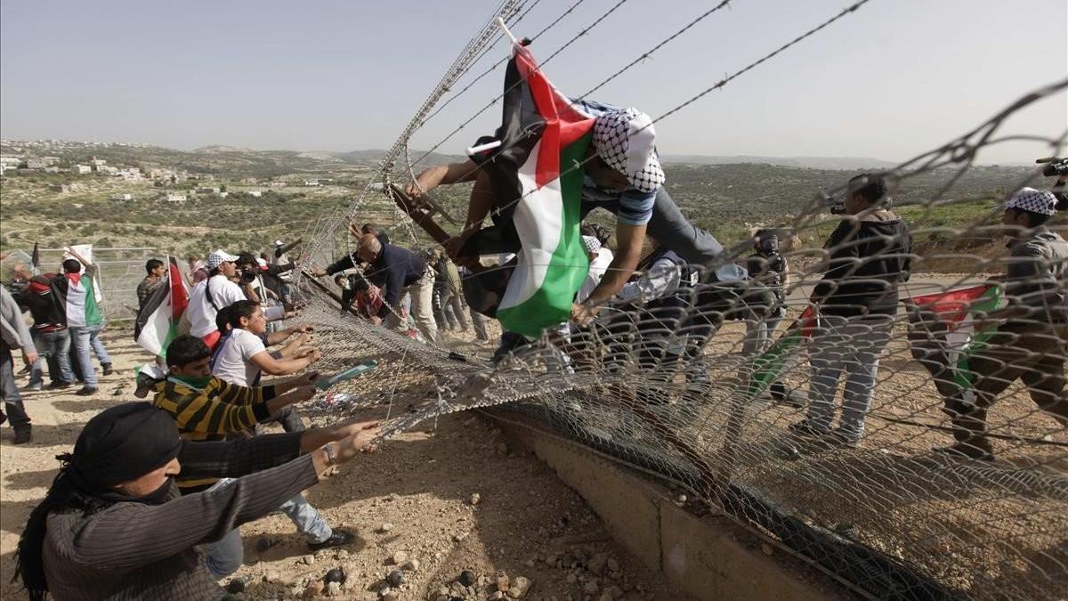 Manifestantes palestinos tratan de derribar una sección de la controvertida barrera israelí durante una protesta en la aldea de Bilin, cerca de Ramala, en Cisjordania.
