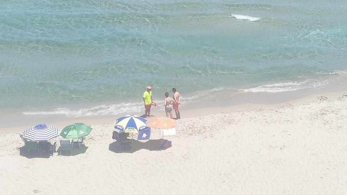 Un vigilante a pie de playa alertando a los bañistas sobre el vertido de aguas fecales que afecta a La Manga.
