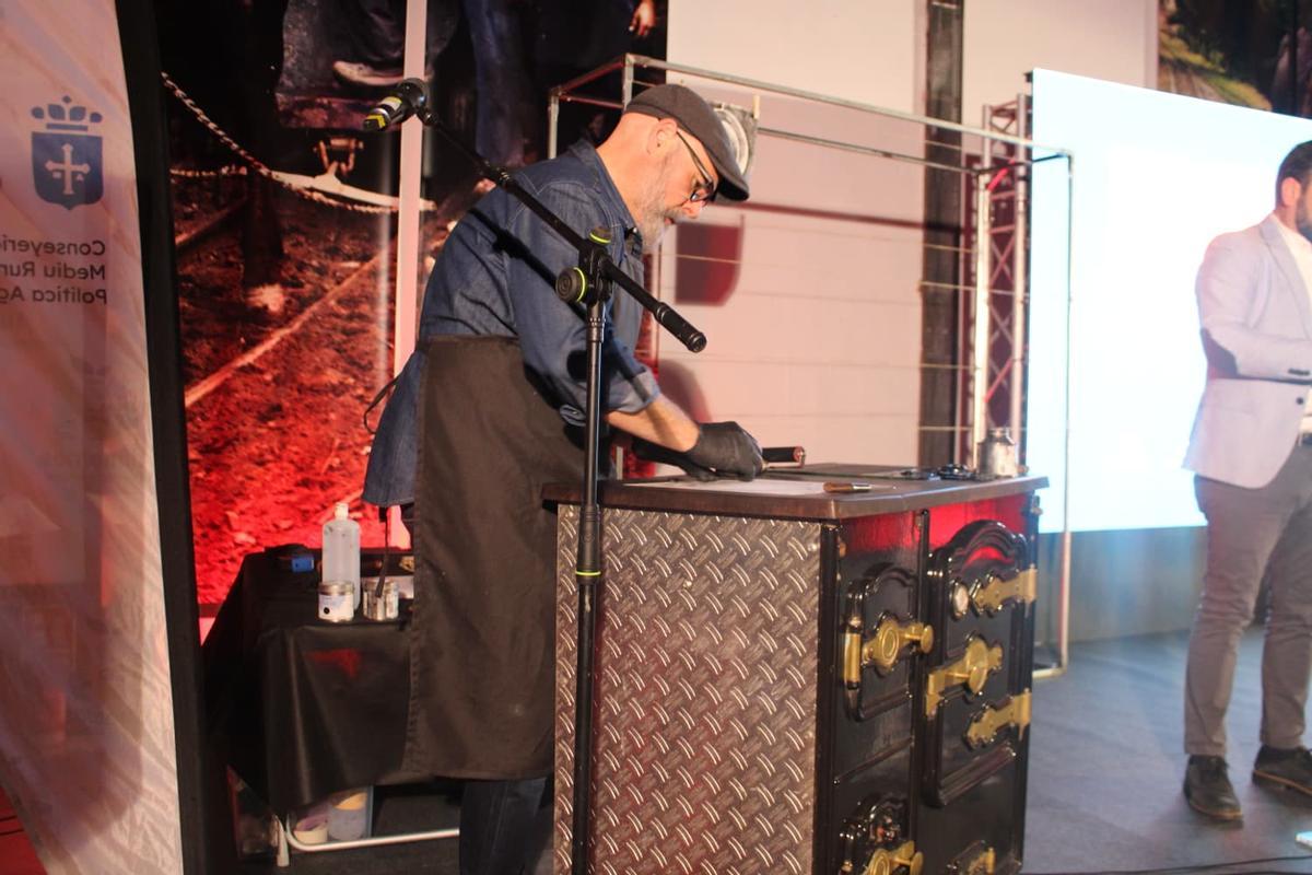 El artista Miguel Díaz hace un dibujo sobre una cocina de carbón.