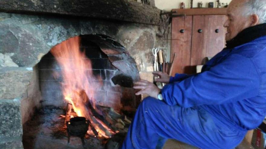 Un hombre alistano se calienta en su chimenea gracias a la leña cortada.