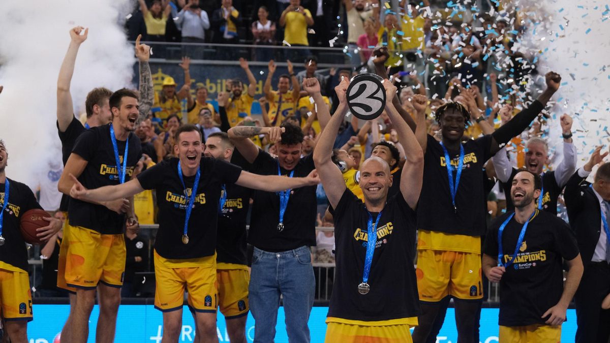 Stevic, capitán del Granca, levanta el trofeo de campeón de la Eurocup con sus compañeros detrás en el podio, el 3 de mayo de 2023 en el Arena.