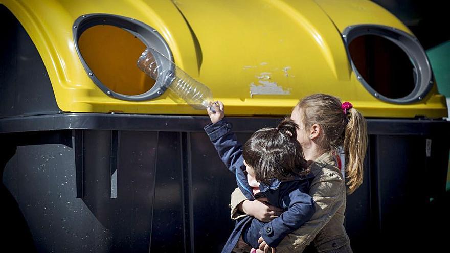 Un niño mete una botella de plástico en el contenedor.  Ecoembes