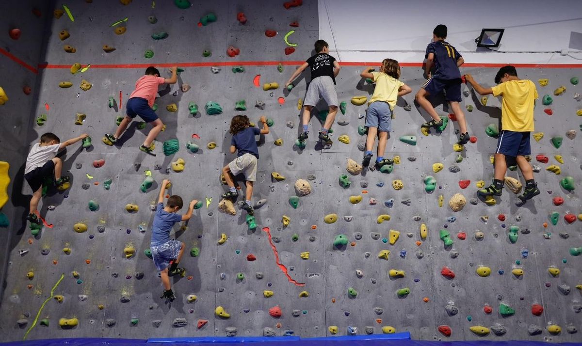 Un grupo de jóvenes escaladores intenta superar un bloque en la sede del club Monkey Rock.