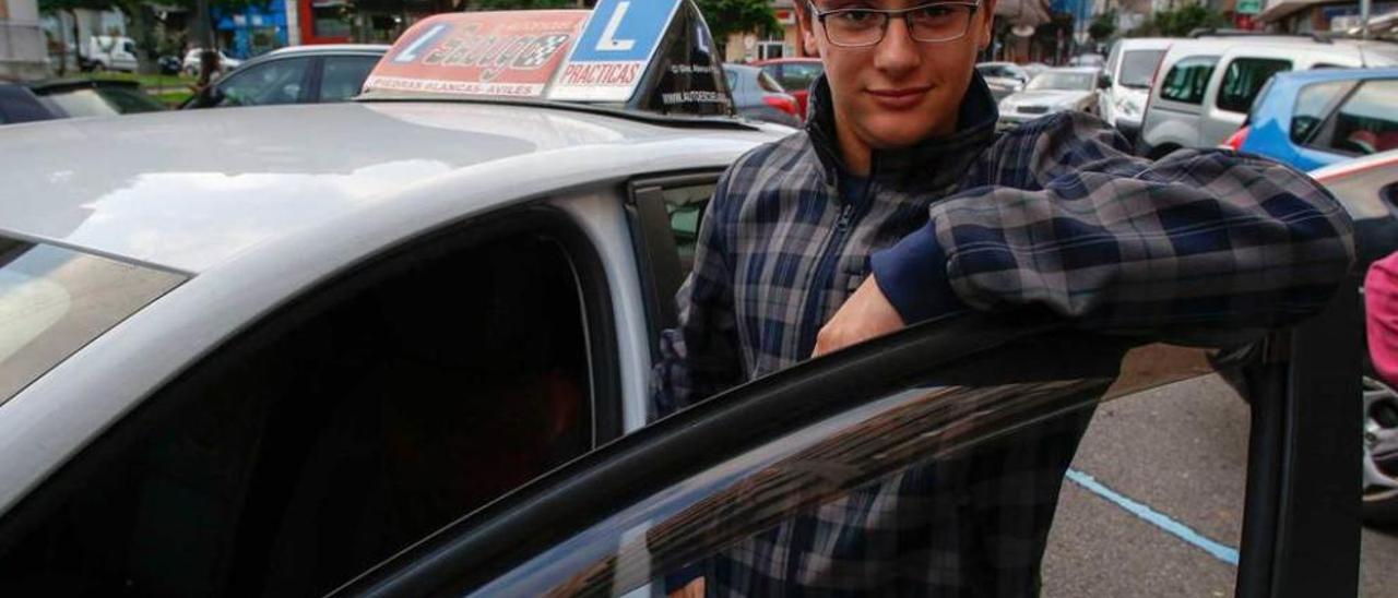 El avilesino Andrés Rodríguez, junto al coche de la autoescuela.