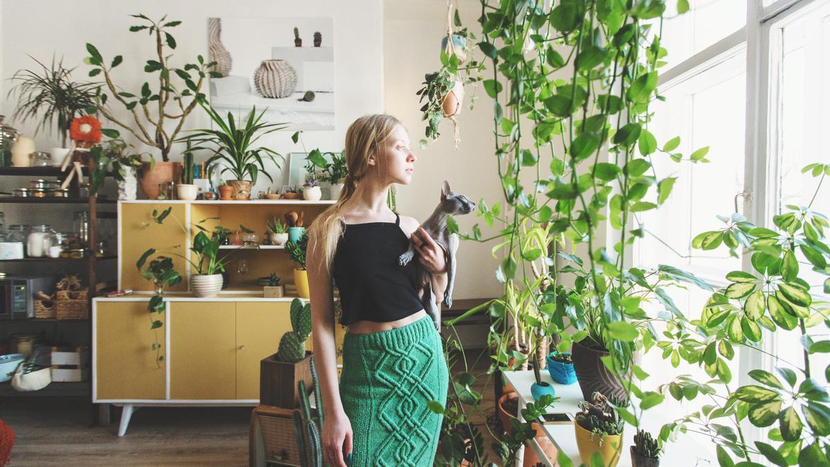 Mujer con un gato, rodeados de plantas