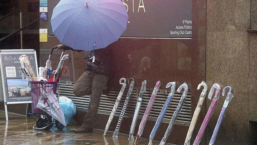 Un vendedor ambulante ofrece paraguas en la calle Real.