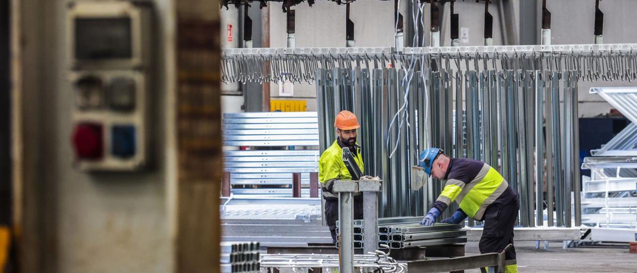 Dos operarios con piezas galvanizadas.