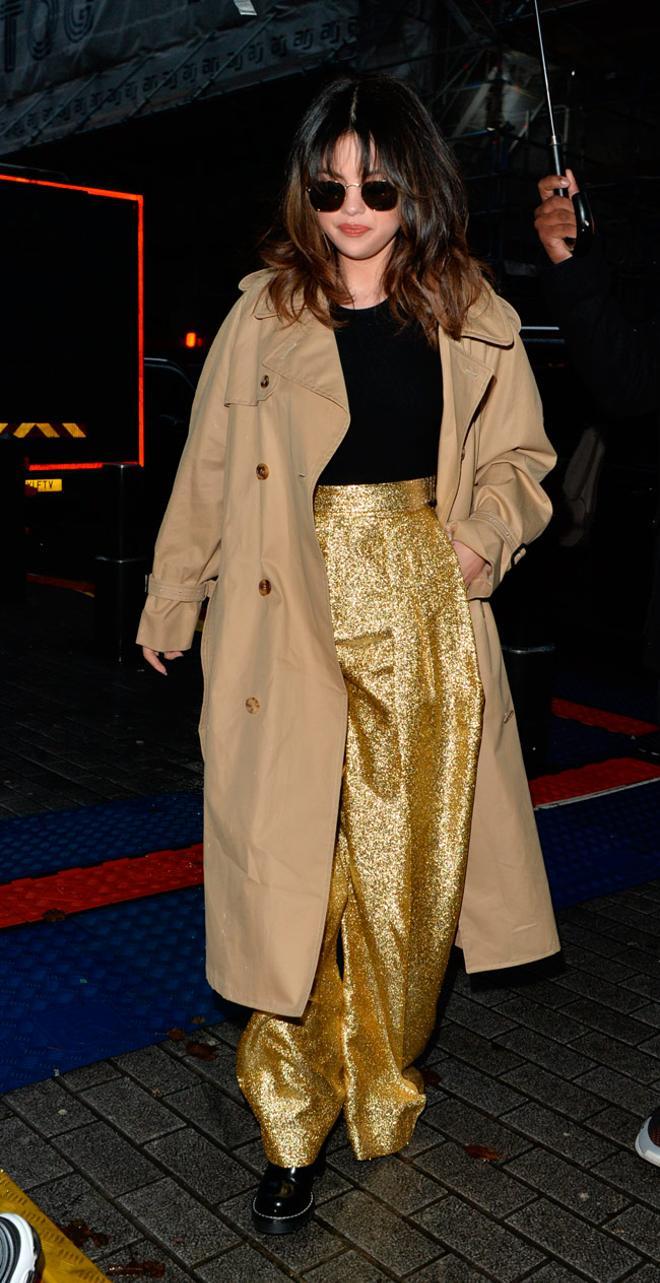 Selena Gomez con pantalones dorados de JW Anderson y gabardina