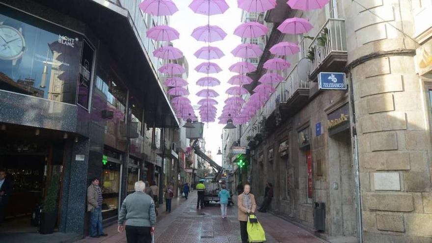 Paraguas de color rosa colocados en la calle de la Oliva por la Aecc. // Rafa Vázquez