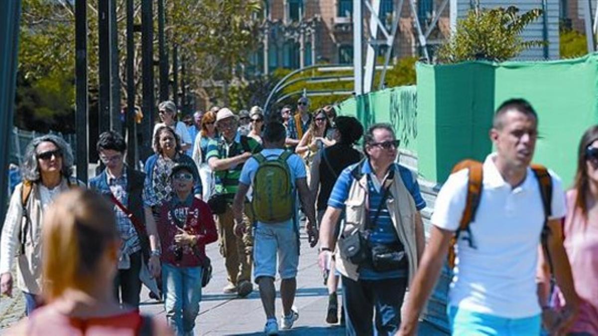 Un grupo de turistas cruza la plaza de Lesseps junto a las vallas de las obras paralizadas de la L-9, ayer.