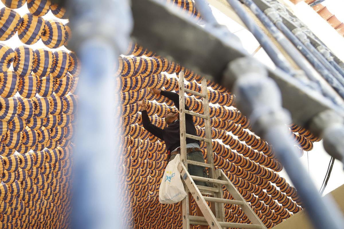 Que no falten los farolillos. Un hombre se afana en colocarlos en una caseta, este martes.