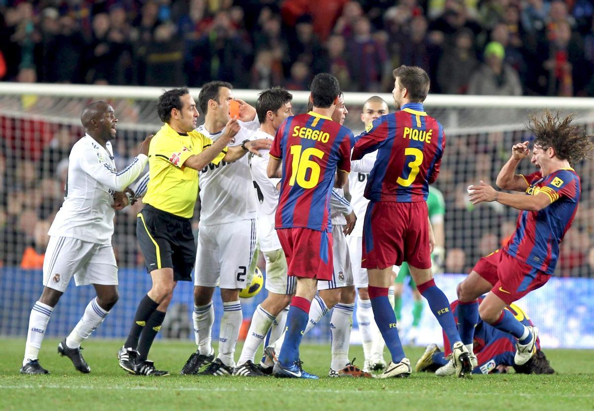 BARCELONA, 29/11/10.- El árbitro Iturralde González (2ºi) muestra la tarjeta roja al defensa del Real Madrid, Sergio Ramos, mientras el capitán del FC Barcelona, Carles Puyol (d) cae empujado durante el partido Liga ante el FC Barcelona disputado esta noche en el Nou Camp, en Barcelona. EFE/Toni Albir ESPAÑA: FUTBOL PRIMERA DIVISIÓN. DEPORTES. FUTBOL. PRIMERA DIVISION. TEMPORADA 2010 - 2011. LIGA. DERBI. CLASICO. REAL MADRID. FUTBOL CLUB BARCELONA. GOLEADA.