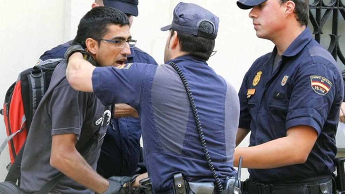 Varios policías retienen a uno de los manifestantes en las inmediaciones de les Corts Valencianes.