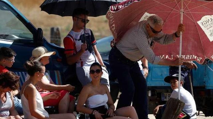 Un grupo de personas busca la sombra en la pradera. En el centro, los caballistas durante un reposo. A la derecha, un toro pasa frente a los aficionados.