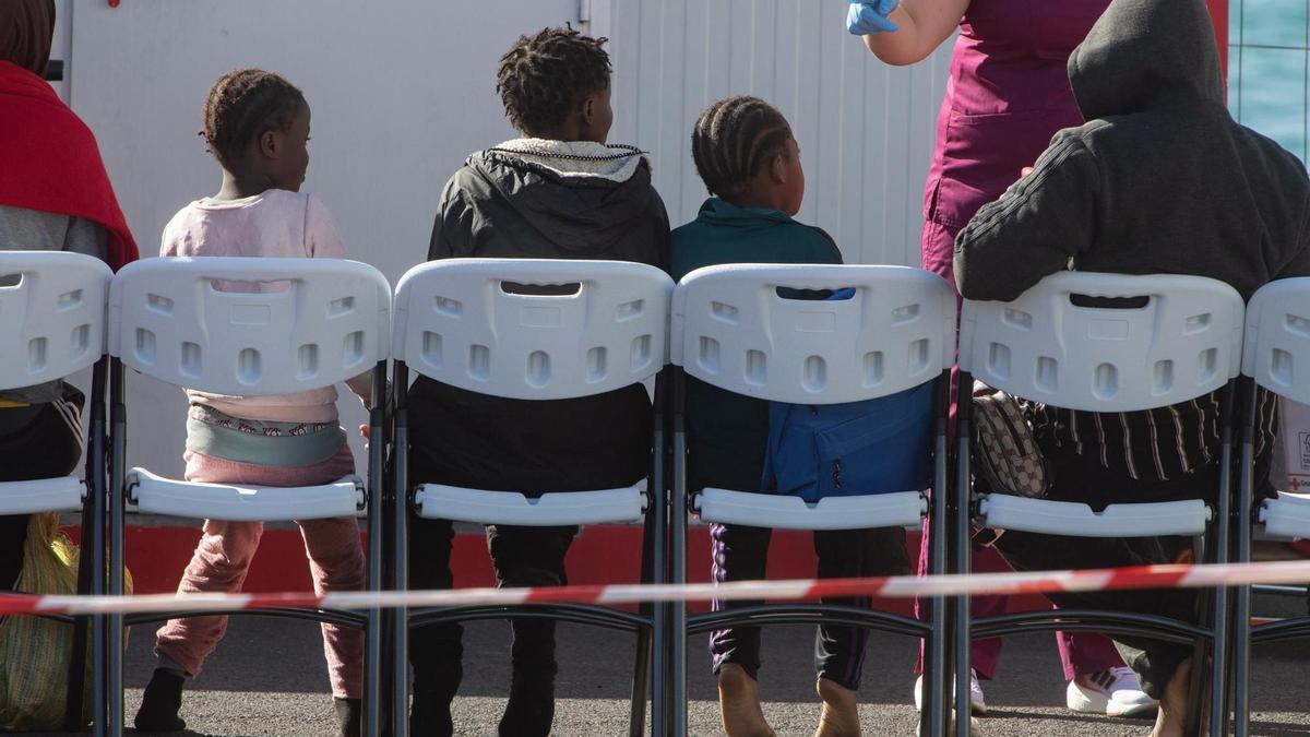 Menores migrantes sentados en unas sillas tras su llegada a Puerto del Rosario.