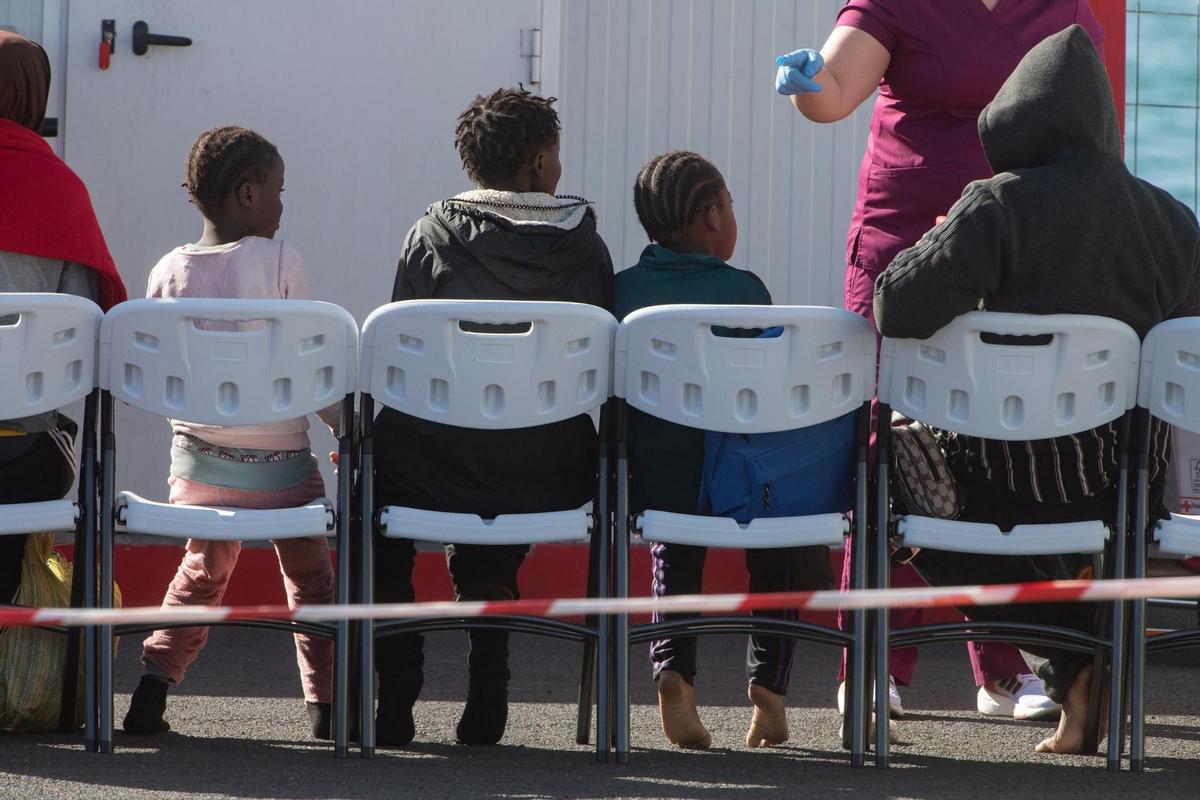 Menores migrantes sentados en unas sillas tras su llegada a Puerto del Rosario.