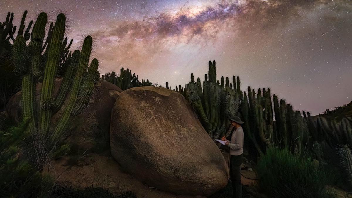Coy junto a unos petroglifos bajo la majestuosidad de la Vía Lactea en el Valle del Encanto de Chile