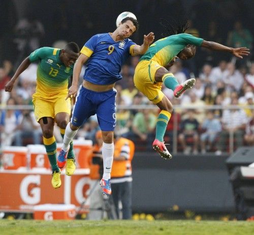 Brazil's Damiao jumps for the ball between South Africa's Dikgacoi and Gaxa during their international friendly soccer match in Sao Paulo