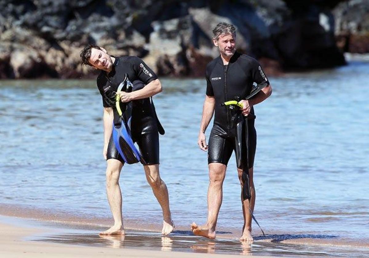 Matt Bomer, quitándose el agua de los oídos y Simon Halls saliendo del agua con su traje de neopreno y sus aletas