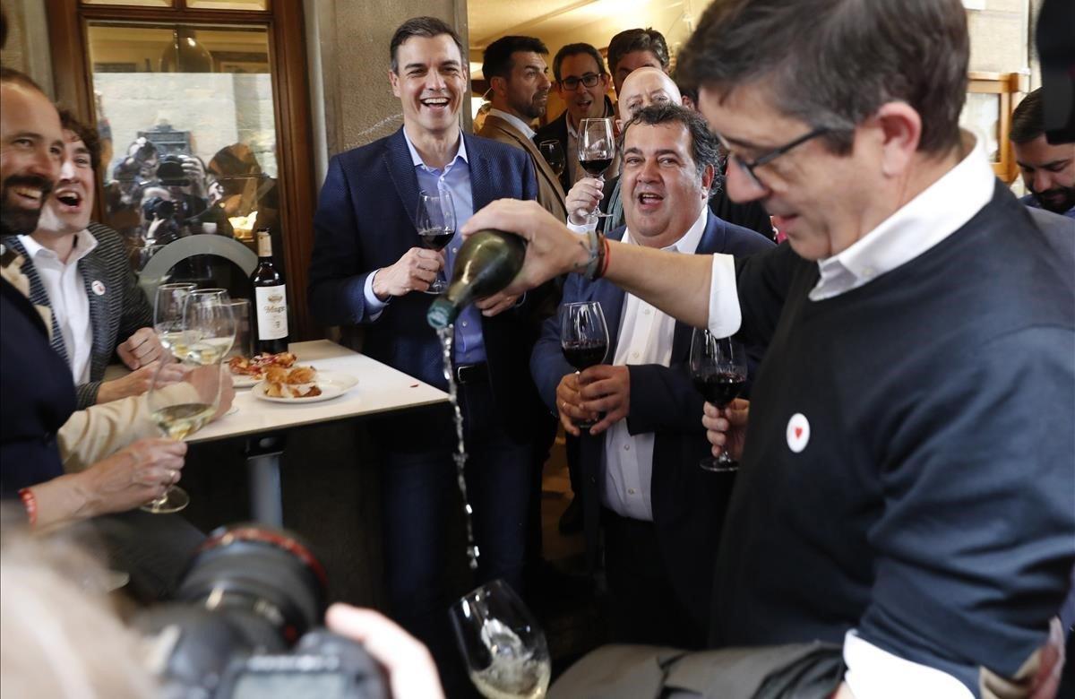 Pedro Sánchez observa al dirigente del PSE-EE, Patxi López que escancia un vaso de txakolí en la Parte Vieja de San Sebastián, tras participar en un acto electoral celebrado en la capital donostiarra.