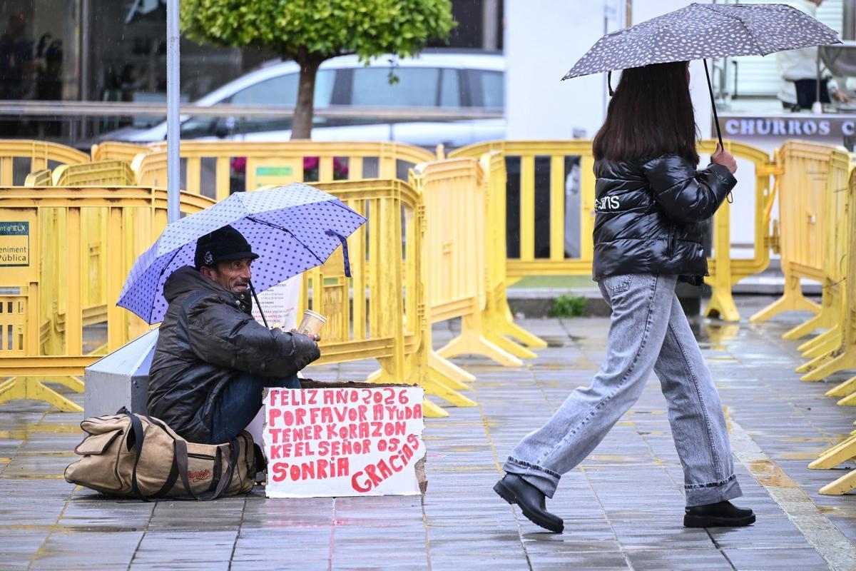 Una persona en la calle resguardada con un paraguas este mismo lunes por la mañana en Elche.