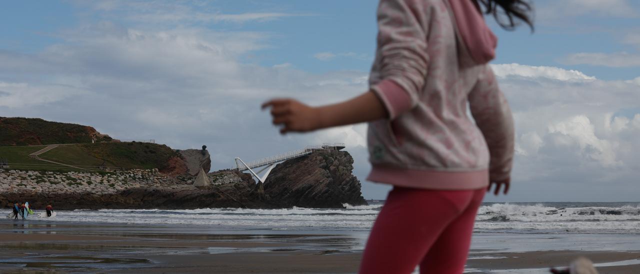 Una niña, en la playa de Salinas, con la Peñona enfrente.