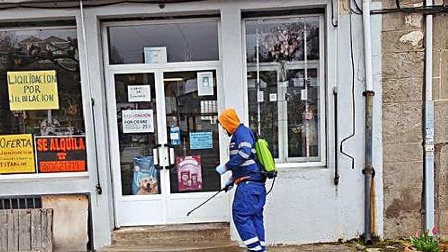 Un operario del Ayuntamiento fumiga la entrada a un comercio.