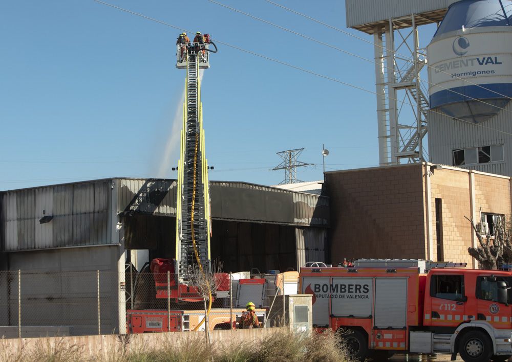 Los bomberos siguen trabajando en la nave del Port de Sagunt un día después del incendio