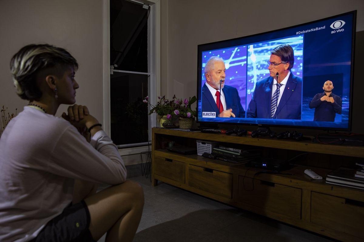 Una mujer sigue el debate electoral entre Lula da Silva y Jair Bolsonaro.