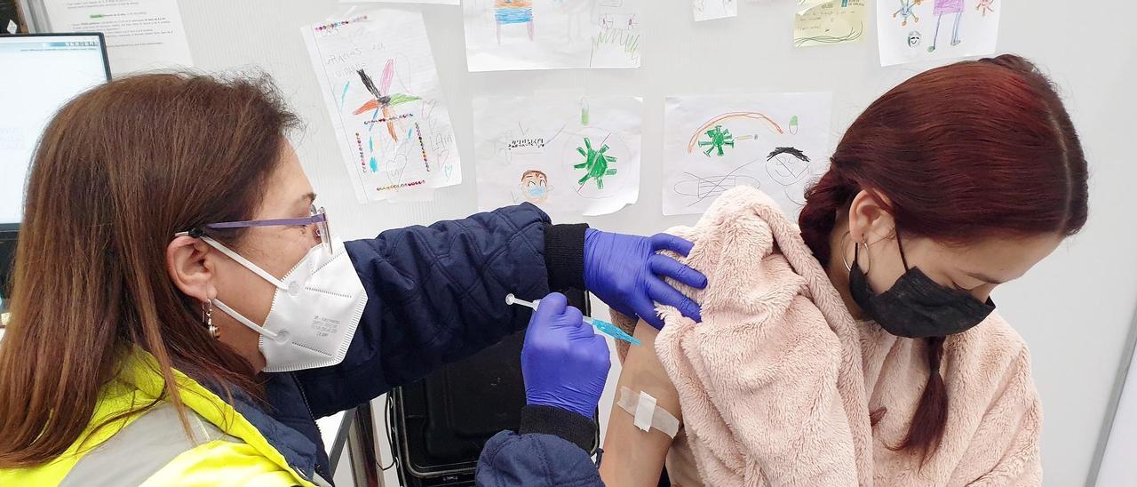 Una joven recibe una dosis de la vacuna del COVID en el último día de la vacunación masiva en Vigo, en primavera.