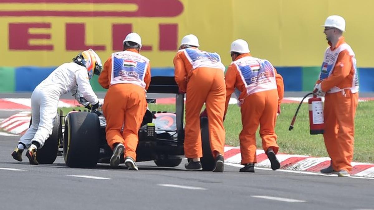 Alonso empuja su coche hasta el 'pit lane'.