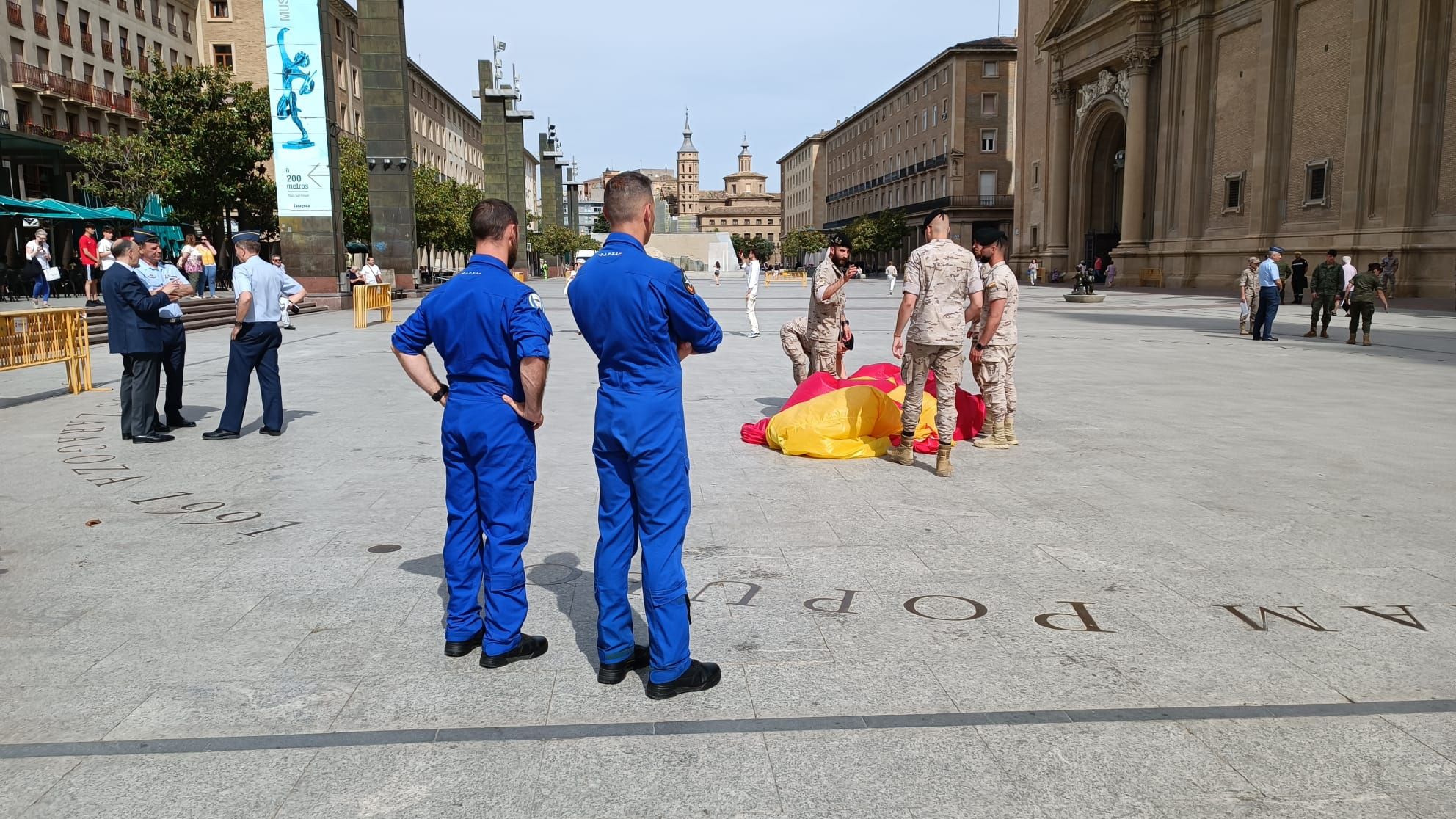 Preparativos para el despliegue aéreo de una bandera de España en la Plaza del Pilar