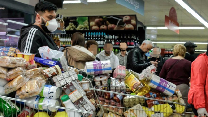 Un home fent cua per pagar amb el carro ple al supermercat.