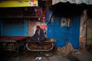 Dos homes dormen, abrigats amb una manta, davant d’una botiga tancada durant un fred matí a Nova Delhi (Índia).