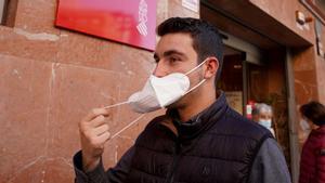 Una persona se quita la mascarilla al salir de un centro de Salud