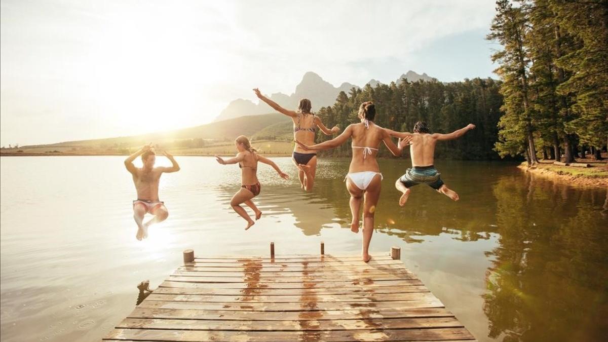 Un grupo de jóvenes saltando a un lago