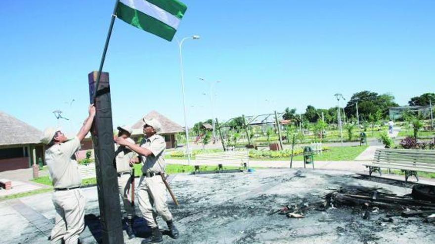 Tres policías reponen la bandera provincial de la autonomista Santa Cruz quemada el domingo por gubernamentales.