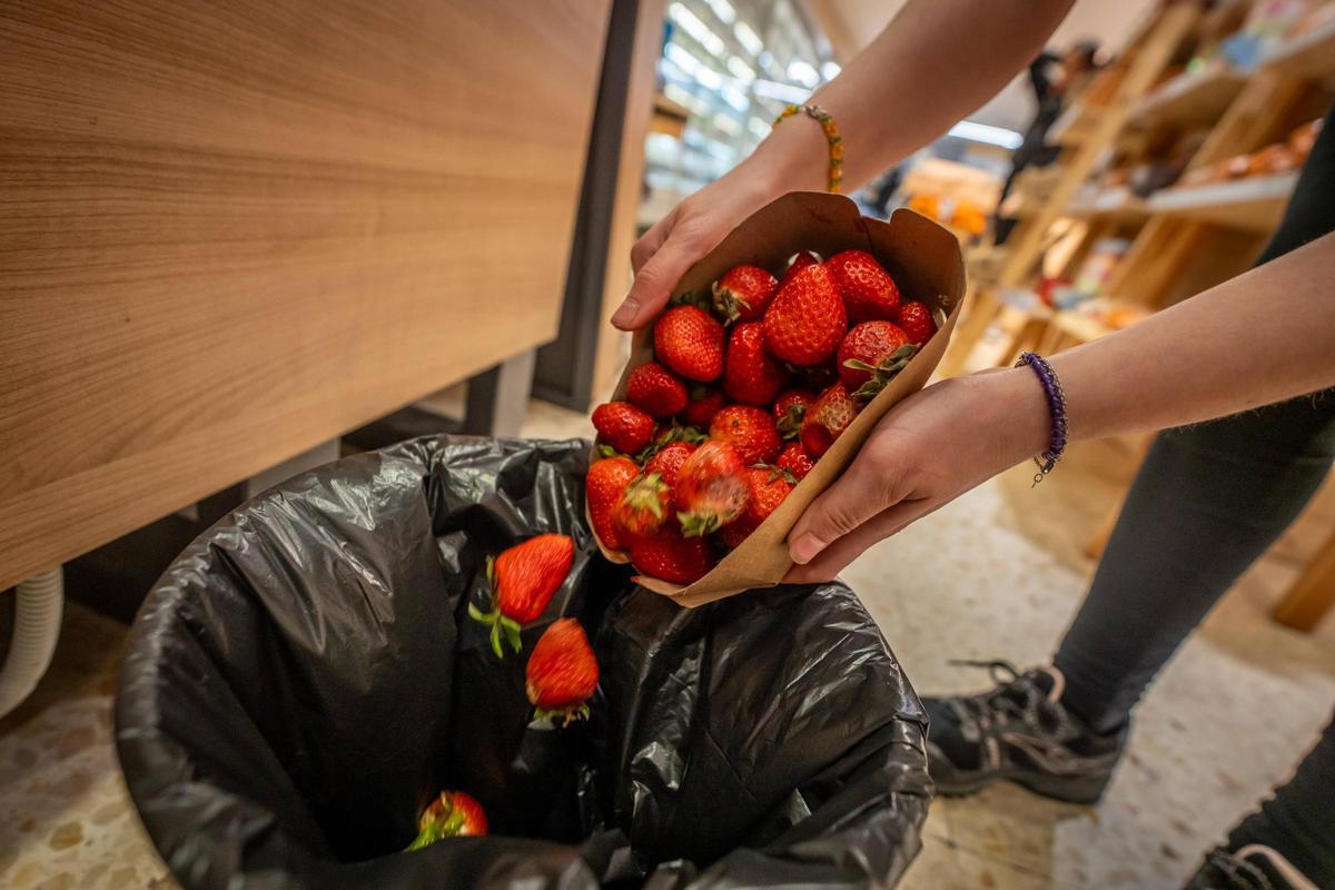 Una persona tira unas fresas.