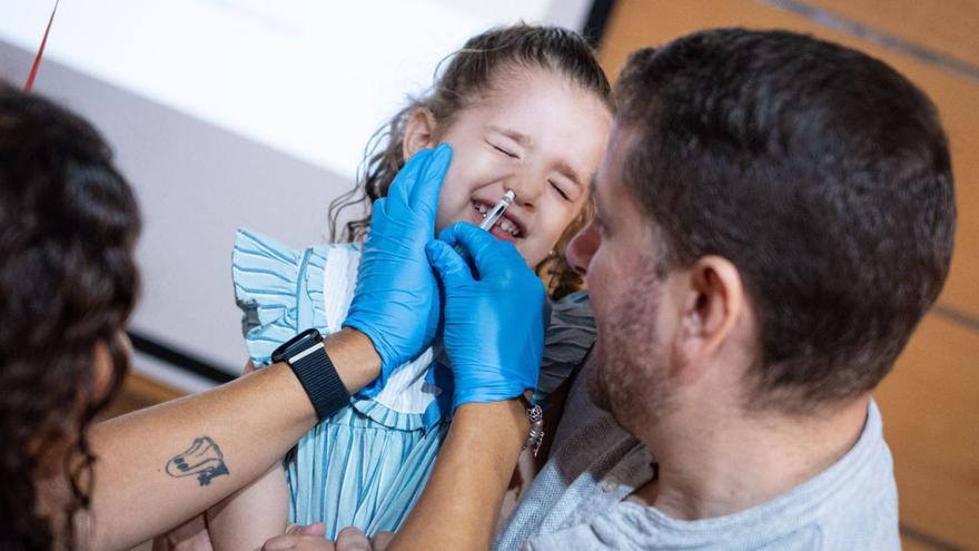 La pequeña Maya durante el momento de su vacunación intranasal, en brazos de su padre.